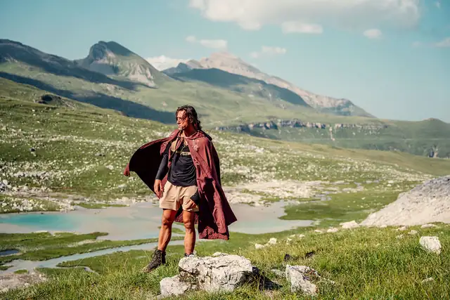 Sol Brah in a red cape on an alpine meadow