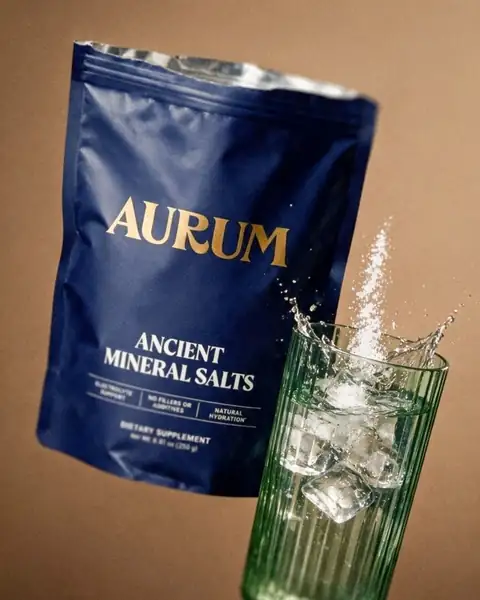 AURUM Ancient Mineral Salts pouch beside a glass of water with a splash